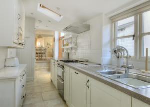 a white kitchen with a sink and a stove at Charm Cottage in Charmouth