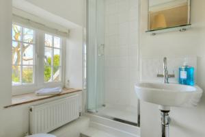 a white bathroom with a sink and a shower at Charm Cottage in Charmouth +9 photos