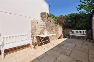 two benches and a table on a patio at Charm Cottage in Charmouth