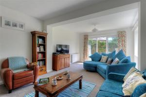 a living room with blue couches and a coffee table at 2 Grange Villas in Charmouth