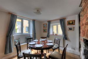 a dining room with a table and chairs and windows at Rona Cottage in Lyme Regis