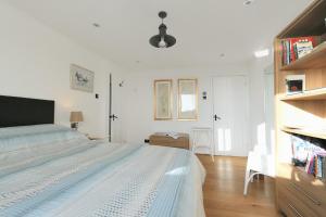 een witte slaapkamer met een bed en een boekenplank bij Dolphins Leap in Charmouth