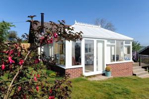 a white conservatory with white windows and a bush at Dolphins Leap in Charmouth