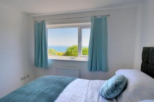a bedroom with a bed and a window with blue curtains at Lottys Lookout in Lyme Regis