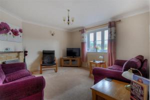 a living room with purple couches and a tv at 4 Riverside Cottages in Charmouth