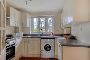 a white kitchen with a washing machine in it at 4 Riverside Cottages in Charmouth +6 photos