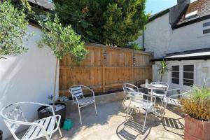 eine Terrasse mit Stühlen, einem Tisch und einem Zaun in der Unterkunft Monmouth Cottage in Lyme Regis + 15 Fotos