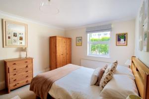 a bedroom with a bed and a dresser and a window at 2 Cobb View in Lyme Regis