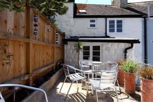 eine Terrasse mit Tisch und Stühlen und einem Zaun in der Unterkunft Monmouth Cottage in Lyme Regis