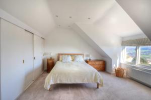 a white bedroom with a bed and a window at Pendower in Charmouth