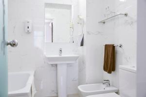 a white bathroom with a sink and a toilet at Hotel Dato in Vitoria-Gasteiz