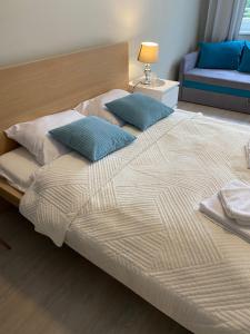 a large bed with two blue pillows on it at Apartament Etna in Kołobrzeg