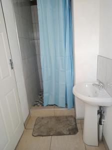 a shower with a blue shower curtain next to a sink at PARK FRONT LODGE in Polokwane