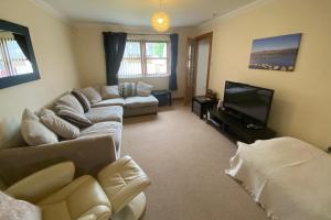 a living room with a couch and a tv at Carn Avie House in Aviemore