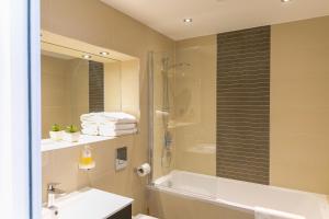 een badkamer met een douche, een wastafel en een bad bij Riverside Stamford Stays in Stamford