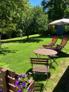 una mesa y dos sillas y una sombrilla en un patio en Le Petit Appartement `a Cariad La Rebeuse, en Corgnac-sur-lʼIsle