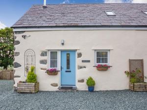 a white cottage with a blue door and flowerpots at Marchlyn in Caernarfon