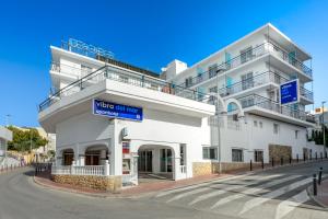 Aparthotel Vibra del Mar - Adults only في سان أنطونيو: مبنى أبيض مع علامة زرقاء أمامه
