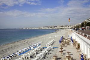 a beach with chairs and umbrellas and the ocean at Novotel Nice Arenas Aeroport in Nice
