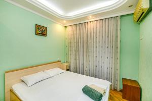 a bedroom with a white bed and green walls at M Estate Targovi Sweet home in Baku