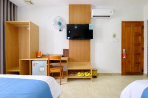 een kamer met een bed en een bureau met een televisie bij Blue Sea Hotel Quy Nhơn - 02 Trần Độc in Quy Nhon
