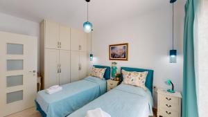 two twin beds in a bedroom with blue at Villa Urania Kamilari in Kamilari +36 photos