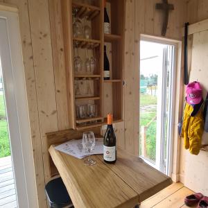 butelka wina na drewnianym blacie ze szklanką w obiekcie Tiny House w mieście Neusiedl an der Zaya