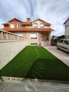 坎加斯德穆拉索的住宿－"A Marosa", bonito chalet dúplex，前面有绿色草坪的房子