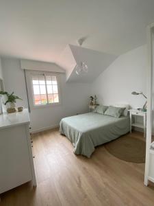 a white bedroom with a bed and a window at "A Marosa", bonito chalet dúplex in Cangas de Morrazo
