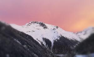 a mountain with snow on it with a pink at Haus Anika Ferienwohnung in Mallnitz