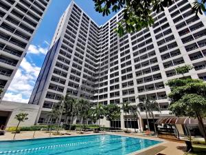a large building with a swimming pool in front of it at Liam's Pad at grace residences in Manila