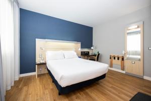 a bedroom with a large white bed and a blue wall at Holiday Inn Express Barcelona City 22@, an IHG Hotel in Barcelona