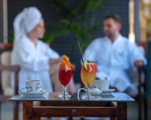 a table with two drinks and a couple in the background at Hotel Fontana Vrnjačka Banja in Vrnjačka Banja