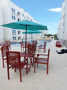 - une table et des chaises avec un parasol à côté de la piscine dans l'établissement Espectacular apartamento en coveñas, à Coveñas