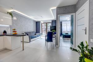 uma cozinha e sala de estar com uma mesa e cadeiras azuis em Apartamenty Silver 4 em Szczecin