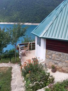 ein Haus mit einer Bank und Blick auf das Wasser in der Unterkunft B&B Konak in Plužine