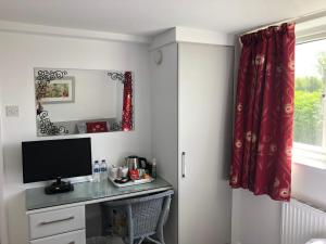 a room with a desk with a television and a window at Acreland Green in Pleshey