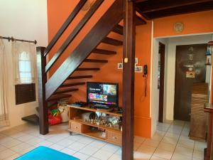 uma sala de estar com uma escada com uma televisão em Excelente casa na Praia do Coqueiro com 4 suítes a 100m da praia em Coqueiro