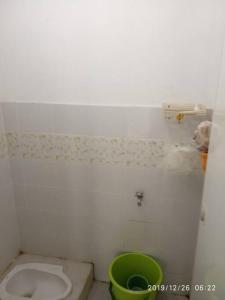 een badkamer met een toilet en een groene emmer bij Nanita Homestay in Talun