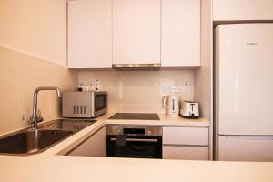 a white kitchen with a sink and a microwave at Phaedrus Living Seaside Luxury Limnaria 172 in Paphos City
