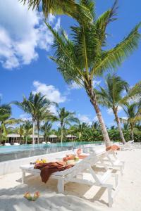 a white picnic table on the beach with palm trees at Mwezi Boutique Resort in Jambiani