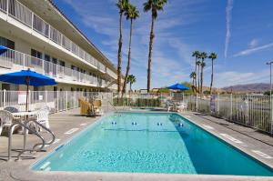 a swimming pool in front of a hotel with palm trees at Motel 6-Twentynine Palms, CA in Twentynine Palms