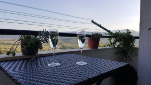 two wine glasses sitting on a table on a balcony at Apartman MODRO JEZERO in Imotski