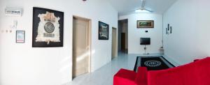 a living room with a red couch and a clock on the wall at WAFID HOMESTAY SERI ISKANDAR in Seri Iskandar