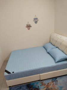 Bett mit blauen Kissen in einem Zimmer in der Unterkunft WAFID HOMESTAY SERI ISKANDAR in Seri Iskandar