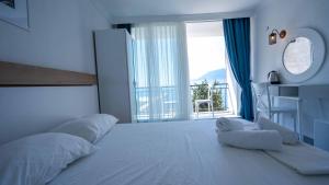 a white bedroom with a large bed and a large window at Sole'n Blu in Kaş