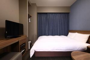 a hotel room with a bed and a flat screen tv at Dormy Inn Express Fujisan Gotemba in Gotemba
