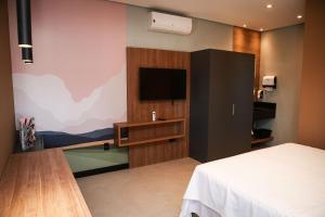 ein Schlafzimmer mit einem Bett und einem TV an der Wand in der Unterkunft Globo Lar Studios in Limeira