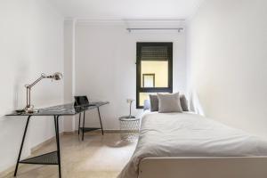 Home2Book Fantastic Design Apartment Las Palmas في لاس بالماس دي غران كاناريا: غرفة نوم بيضاء مع سرير ومكتب