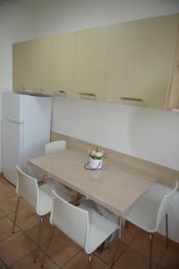 una mesa con sillas blancas y un jarrón de flores. en Appartamento Laura, en Merano